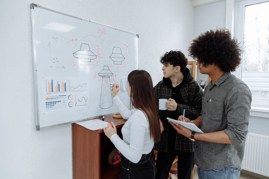 Young professionals brainstorming and designing a product prototype on a whiteboard.
